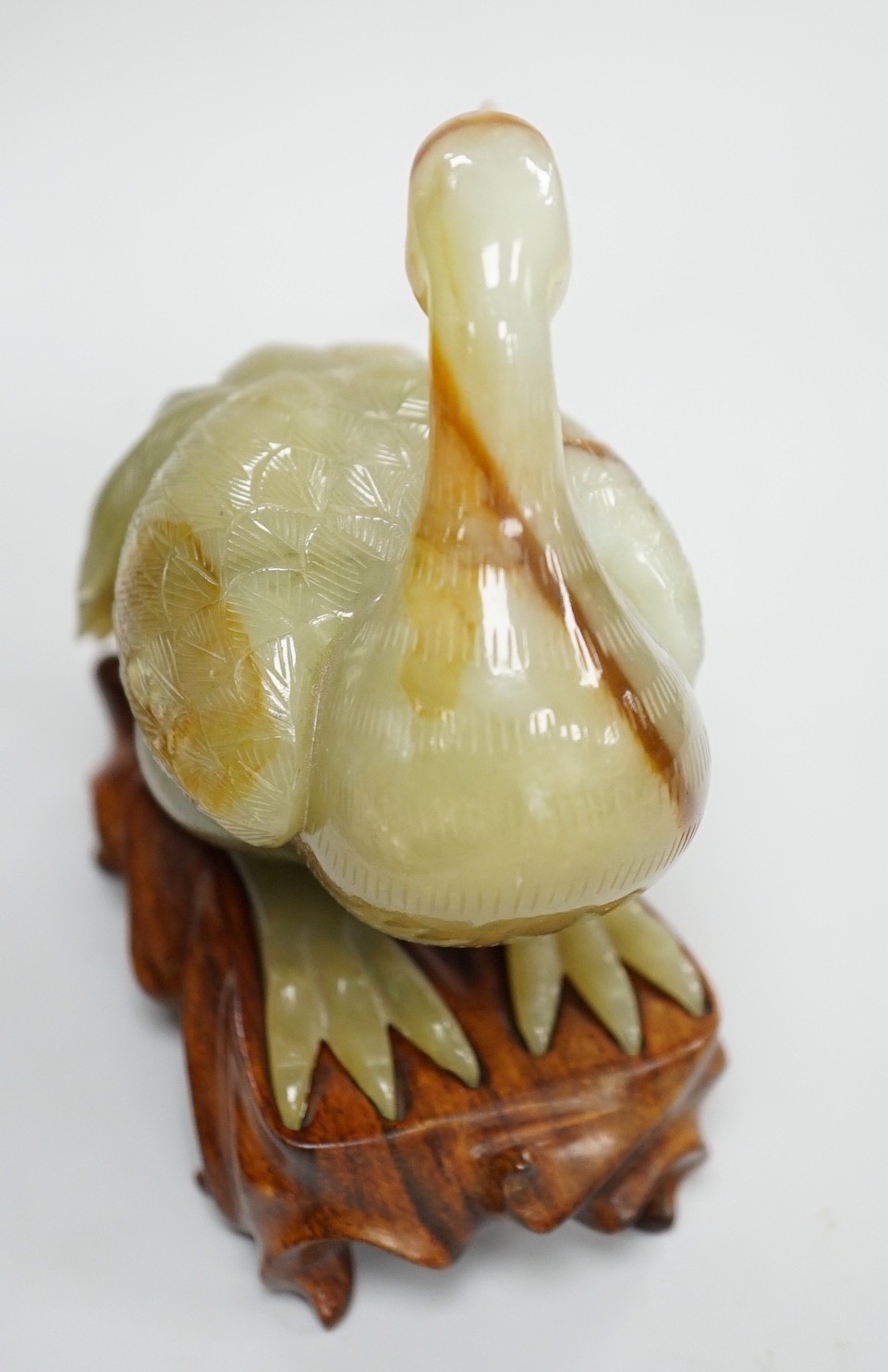 A Chinese green and russet jade figure of a crane, 11.5cm long, wood stand